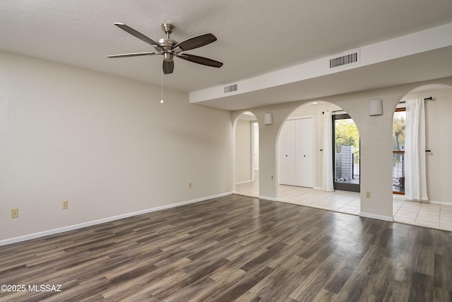spare room with visible vents, a ceiling fan, arched walkways, and wood finished floors