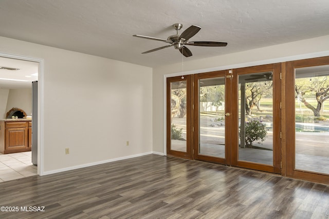 spare room featuring visible vents, baseboards, wood finished floors, and ceiling fan