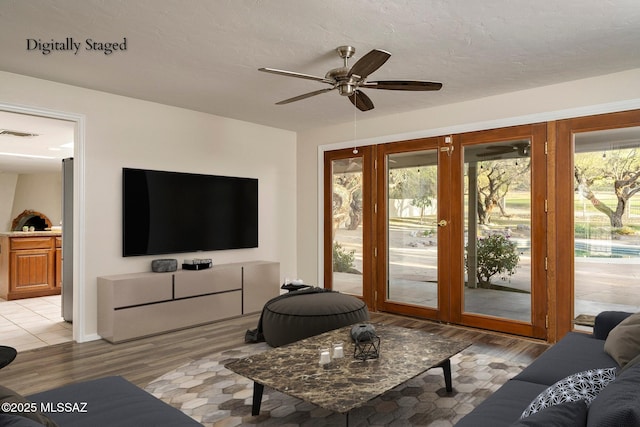 living room featuring light wood finished floors, visible vents, a ceiling fan, and a healthy amount of sunlight