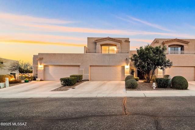 pueblo revival-style home with a balcony and a garage