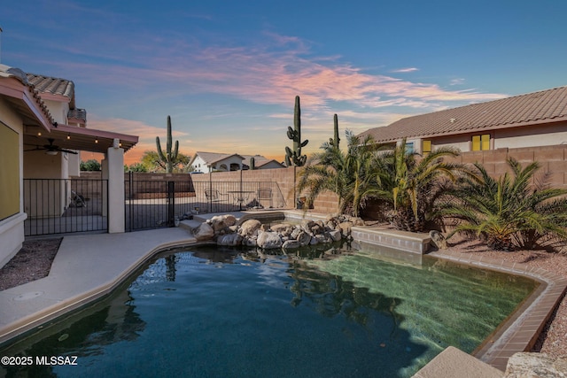 pool at dusk with a fenced backyard, a patio area, a fenced in pool, and ceiling fan