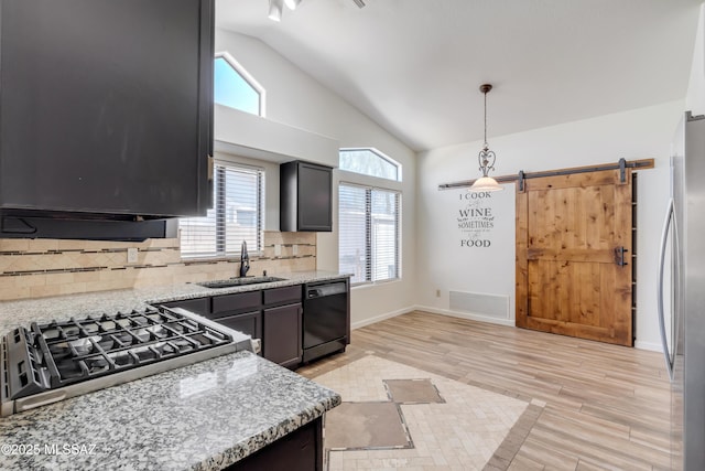 kitchen with sink, dishwasher, light stone counters, a barn door, and pendant lighting