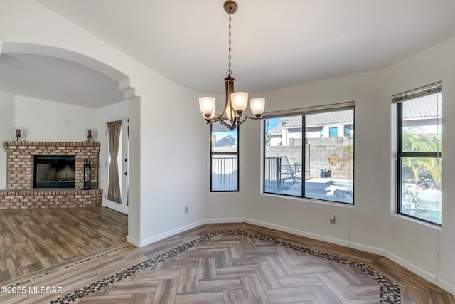 unfurnished dining area with a fireplace, an inviting chandelier, and parquet floors