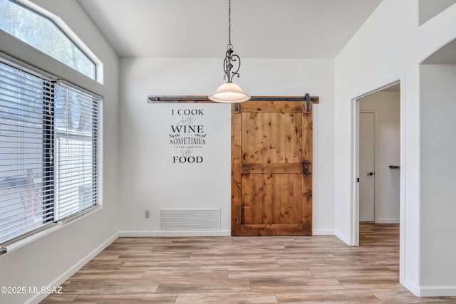 unfurnished dining area with light wood-type flooring and a barn door