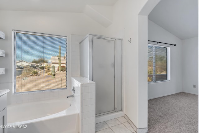 bathroom featuring tile patterned floors, lofted ceiling, vanity, and shower with separate bathtub