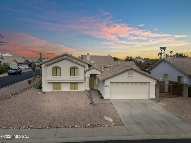 view of front of property with fence, a tiled roof, stucco siding, an attached garage, and driveway