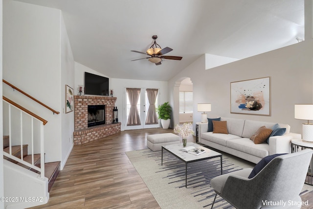 living room with ceiling fan, lofted ceiling, a fireplace, and wood-type flooring