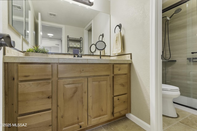 bathroom featuring toilet, vanity, tile patterned floors, and a shower with shower door