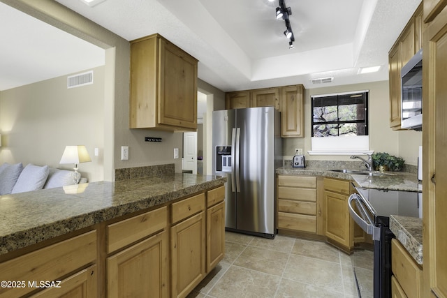 kitchen featuring stainless steel appliances, track lighting, a raised ceiling, and sink