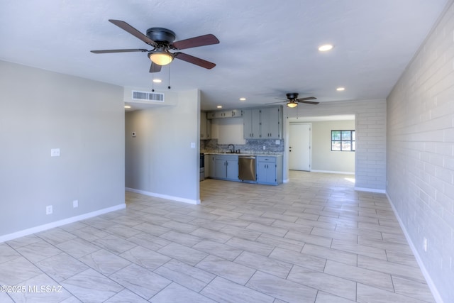 unfurnished living room featuring brick wall, ceiling fan, and sink