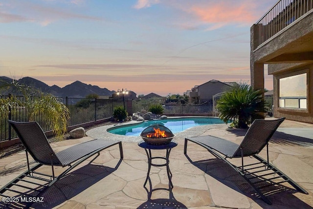 pool at dusk with an outdoor fire pit and a patio area