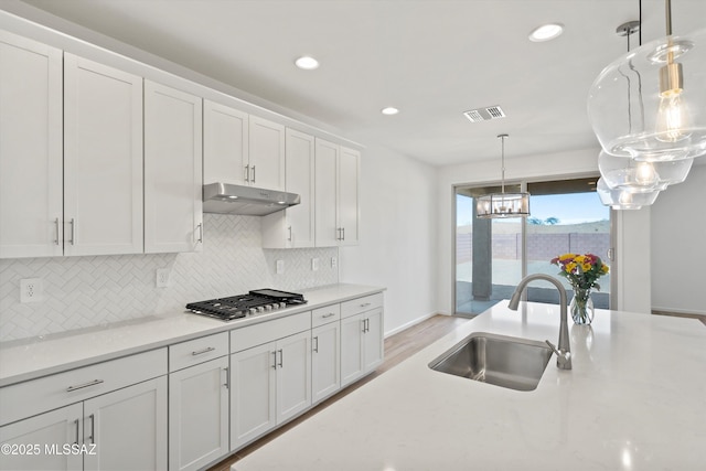 kitchen with decorative light fixtures, sink, white cabinetry, and stainless steel gas stovetop