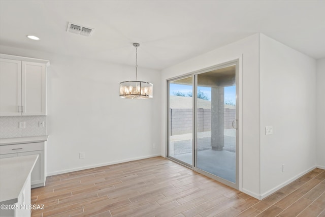 unfurnished dining area featuring light wood-type flooring and a notable chandelier