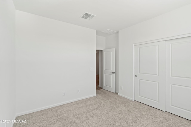 unfurnished bedroom featuring light carpet and a closet