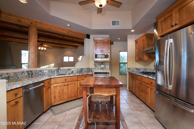 kitchen featuring butcher block counters, light tile patterned floors, decorative backsplash, wall chimney range hood, and appliances with stainless steel finishes