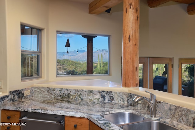 kitchen featuring a mountain view, light stone countertops, beamed ceiling, and sink