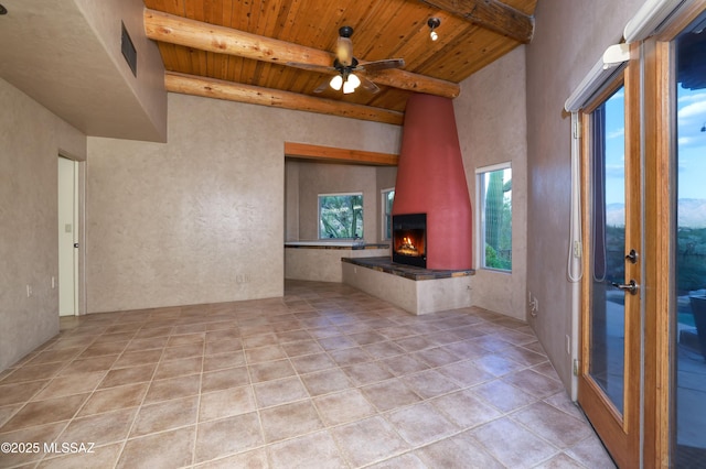 unfurnished living room with beamed ceiling, a fireplace, ceiling fan, and wood ceiling