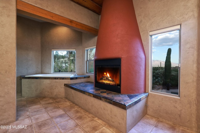 bathroom featuring a fireplace, a healthy amount of sunlight, and beam ceiling