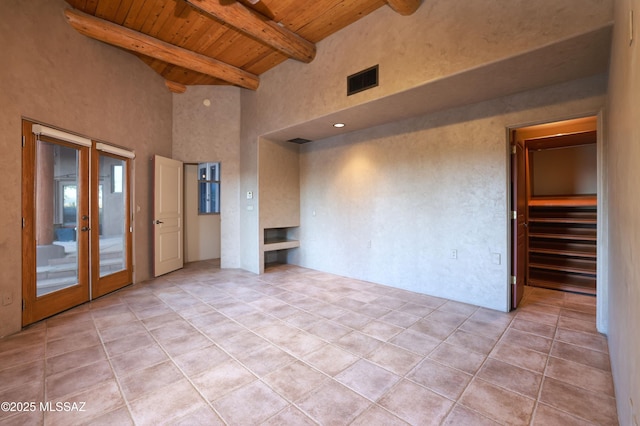 spare room featuring french doors, wood ceiling, a towering ceiling, light tile patterned flooring, and beamed ceiling