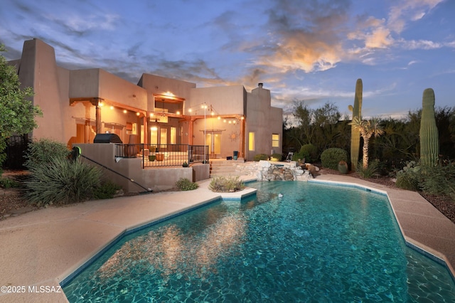 pool at dusk featuring a patio