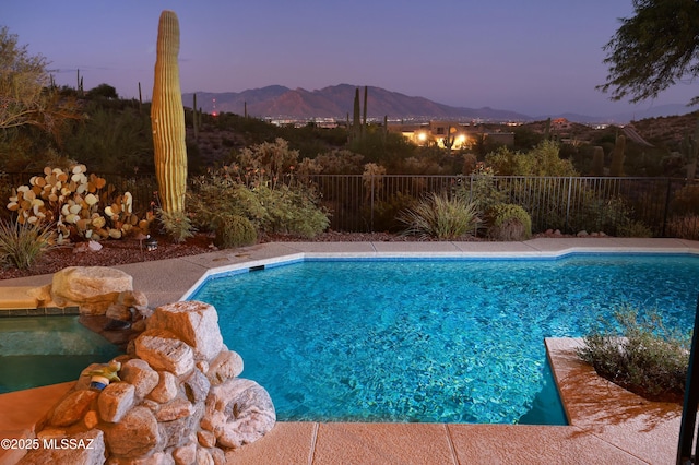 pool at dusk featuring a mountain view