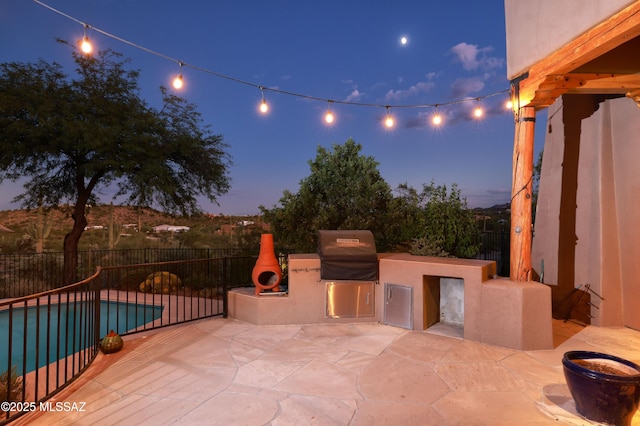 patio terrace at dusk with a grill, an outdoor fireplace, a fenced in pool, and area for grilling