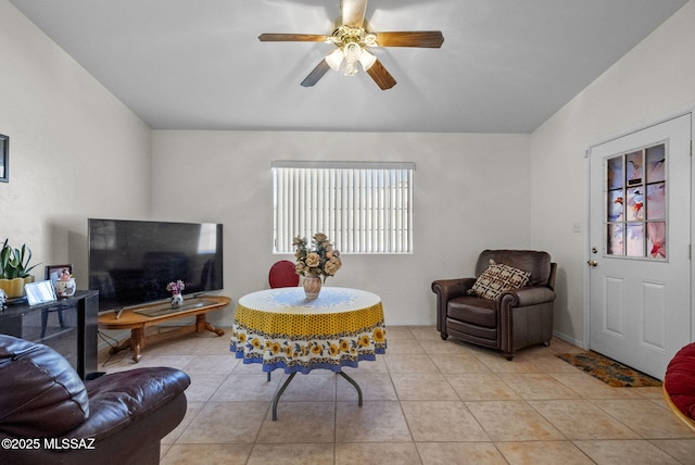 living room with a ceiling fan, lofted ceiling, and light tile patterned floors