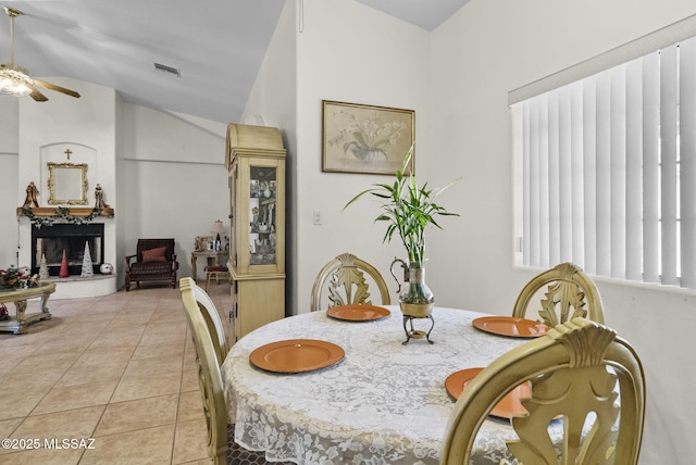 dining space with a ceiling fan, light tile patterned floors, visible vents, and vaulted ceiling