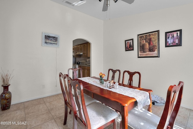 dining room featuring light tile patterned floors, visible vents, a ceiling fan, and arched walkways