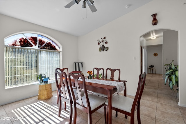 dining room featuring ceiling fan, lofted ceiling, arched walkways, and light tile patterned floors