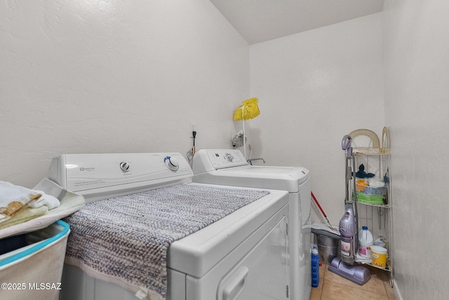 washroom featuring washing machine and dryer, laundry area, and light tile patterned flooring