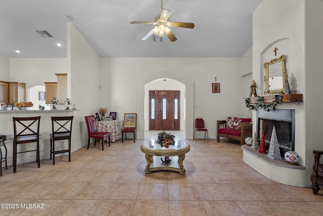 entryway with light tile patterned flooring, a ceiling fan, a fireplace with raised hearth, and visible vents