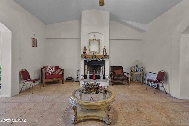 tiled living room featuring vaulted ceiling, arched walkways, and a fireplace with raised hearth