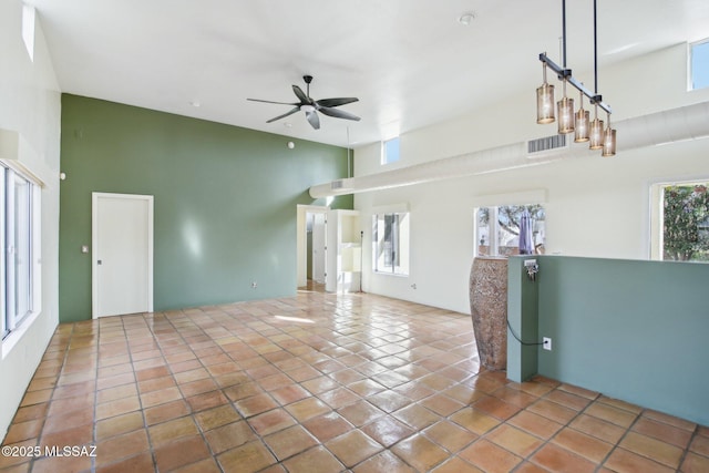 unfurnished living room featuring ceiling fan, a high ceiling, a wealth of natural light, and tile patterned floors