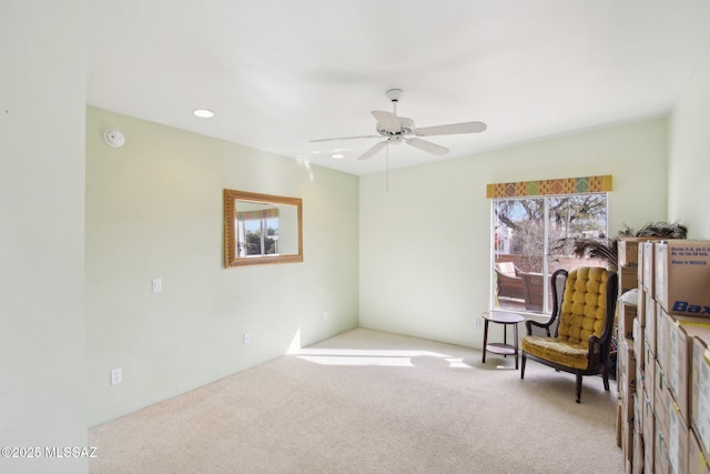 living area with light colored carpet and ceiling fan