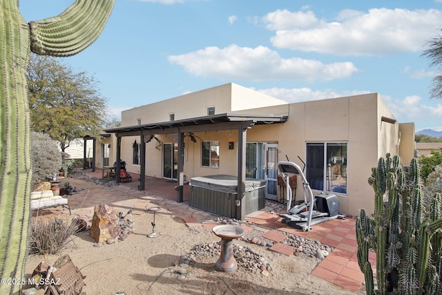 back of property with a hot tub and a patio