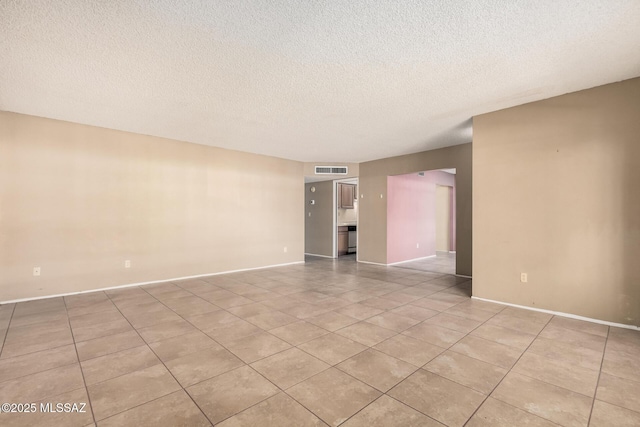 unfurnished room with a textured ceiling and light tile patterned floors