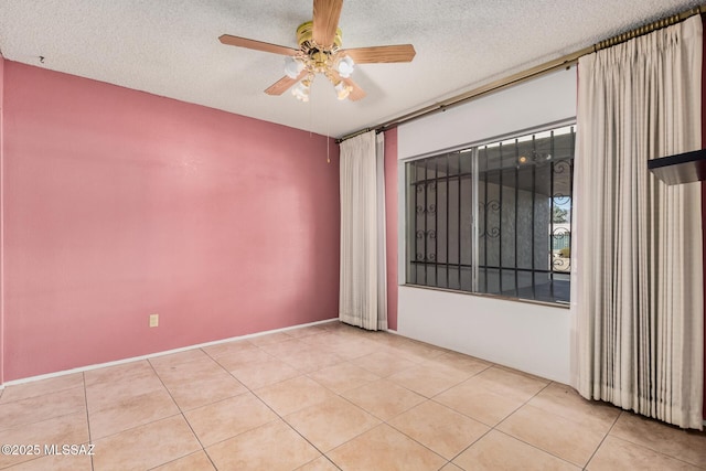 empty room with a textured ceiling, ceiling fan, and light tile patterned flooring