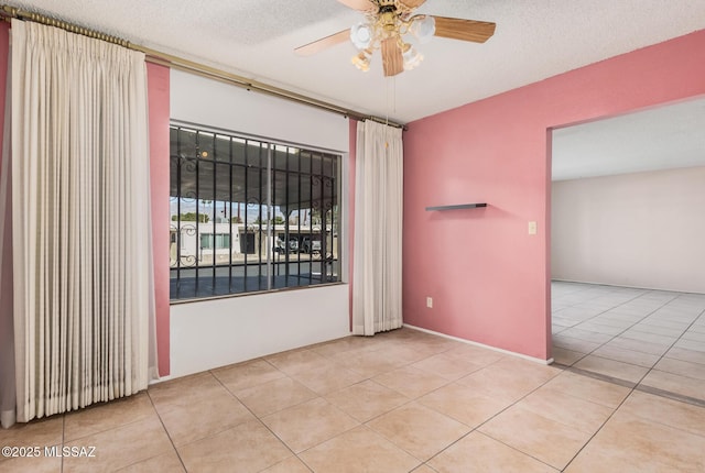 tiled spare room with a textured ceiling and ceiling fan