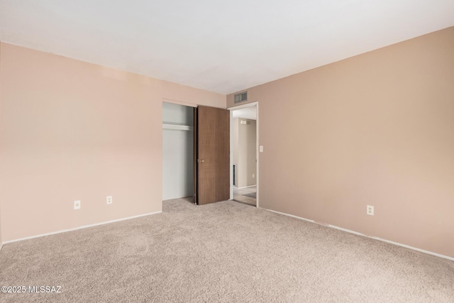 unfurnished bedroom featuring light colored carpet and a closet