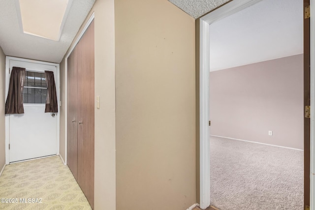 hall featuring a textured ceiling and light carpet