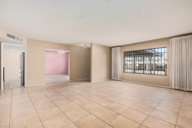 unfurnished room featuring a textured ceiling and light tile patterned floors