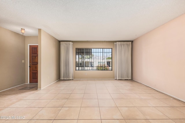 empty room featuring a textured ceiling and light tile patterned floors