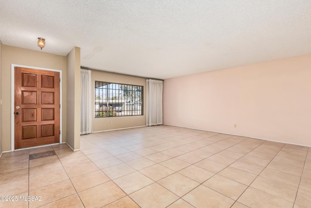 foyer entrance with a textured ceiling and light tile patterned floors