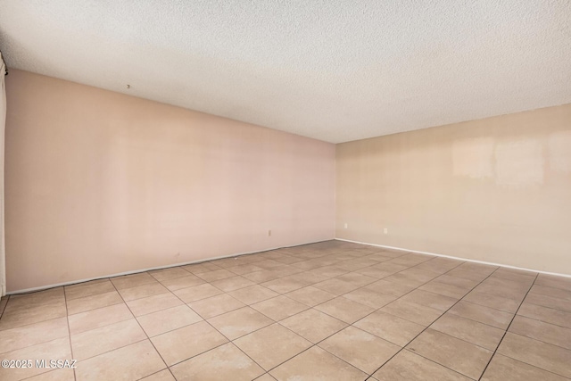 spare room with a textured ceiling and light tile patterned floors