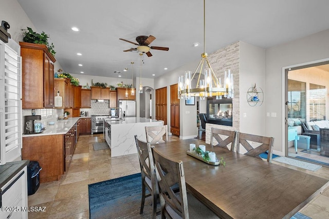 dining area with arched walkways, baseboards, recessed lighting, and ceiling fan with notable chandelier