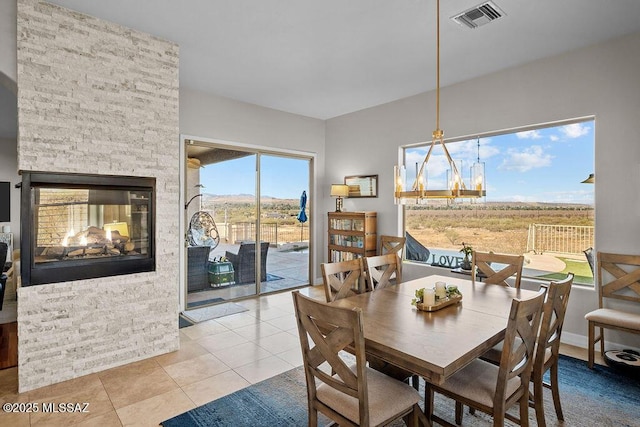 dining area featuring a stone fireplace, tile patterned flooring, and visible vents