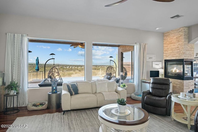 living room with visible vents, wood finished floors, a wealth of natural light, and a multi sided fireplace