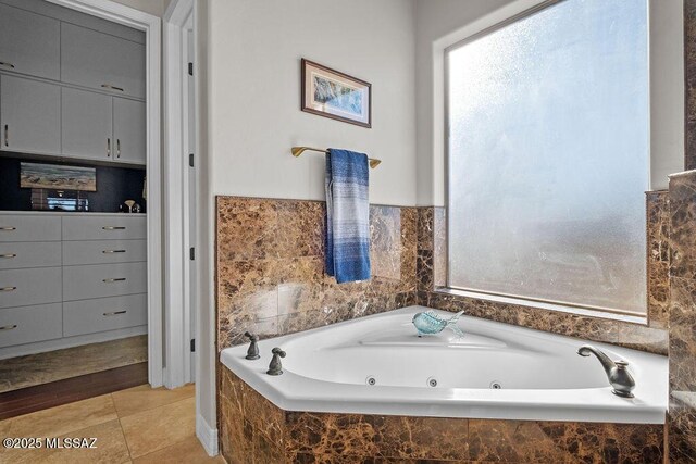 bathroom with a tub with jets and tile patterned floors