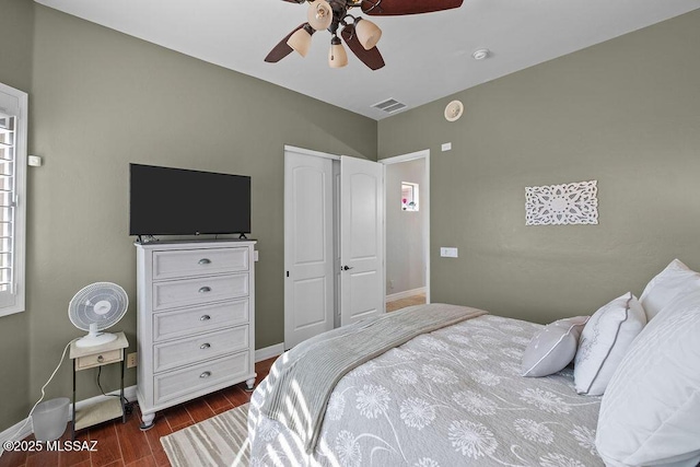 bedroom with baseboards, visible vents, ceiling fan, and dark wood-type flooring